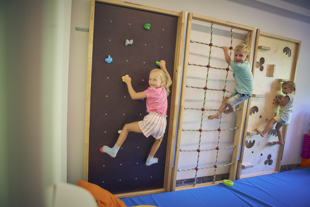 Kinder klettern im Indoor-Spielbereich an Kletterwand und Seilnetz